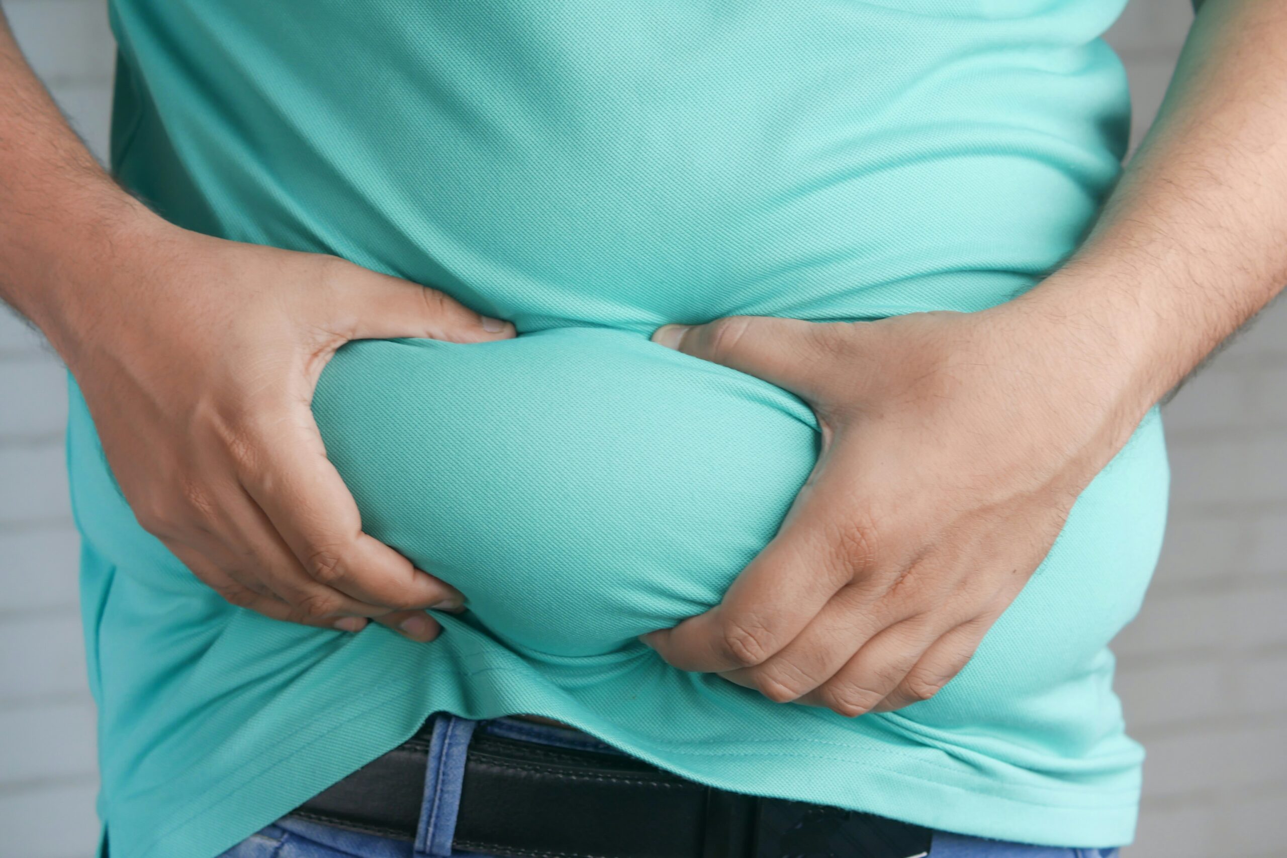 Man grabbing belly fat showing the effects of weight loss after 40