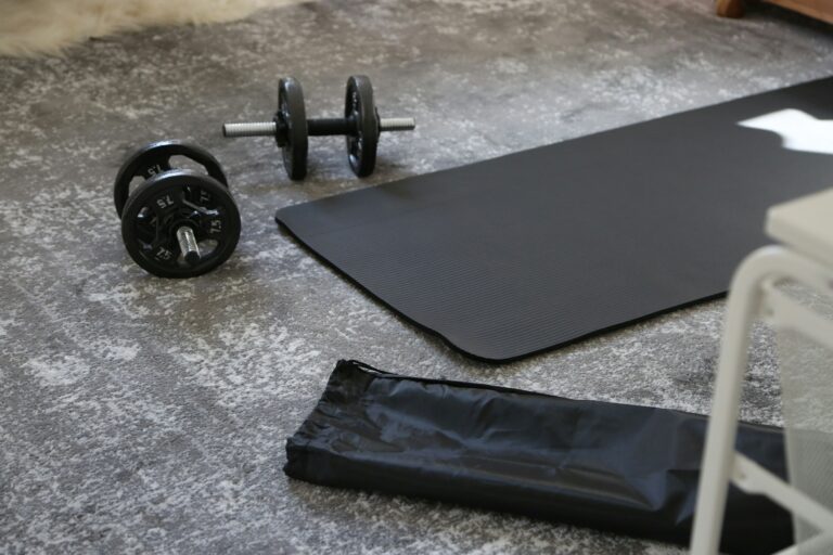 Home gym equipment including dumbbells exercise mat and resistance bands on a garage floor