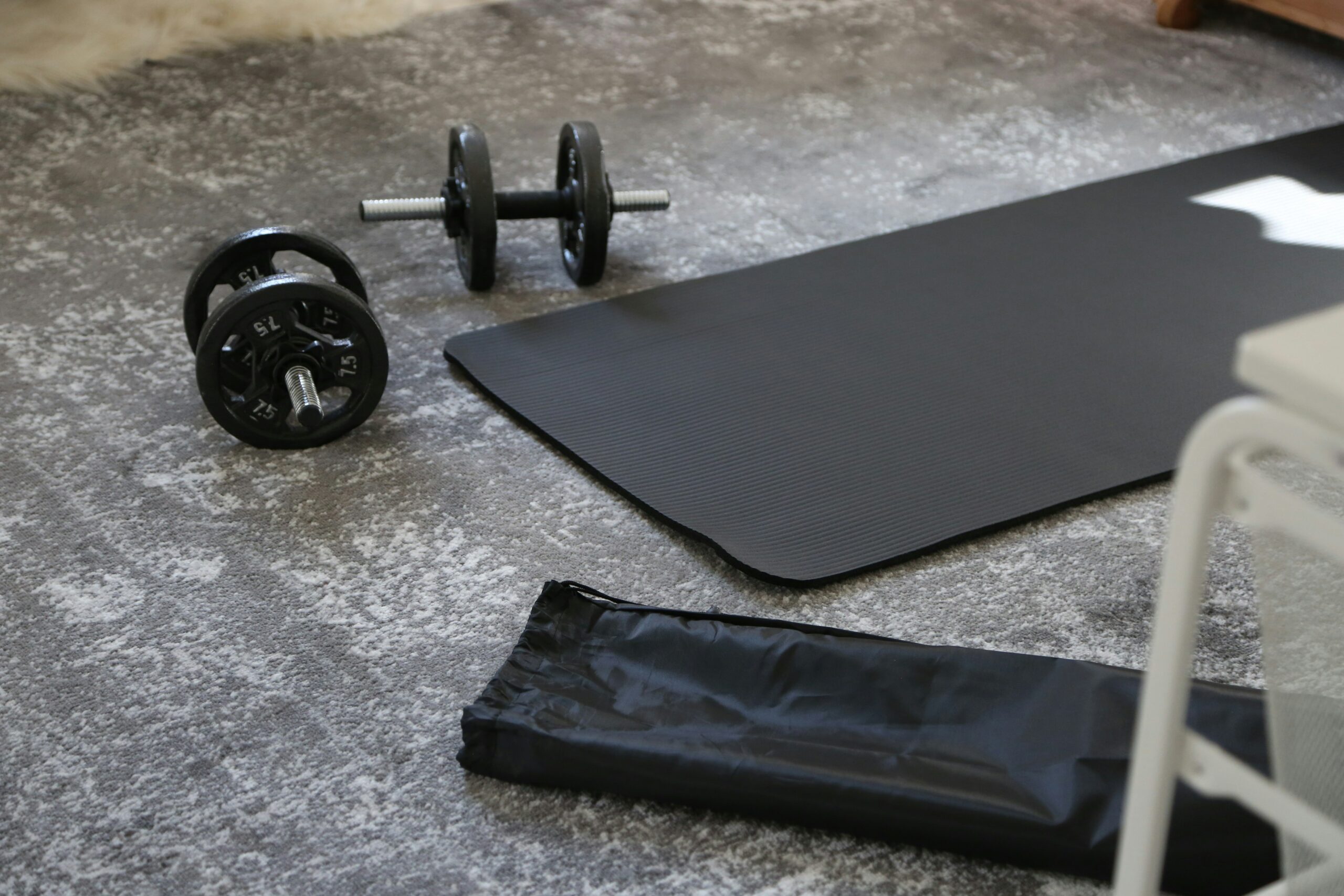 Home gym equipment including dumbbells exercise mat and resistance bands on a garage floor