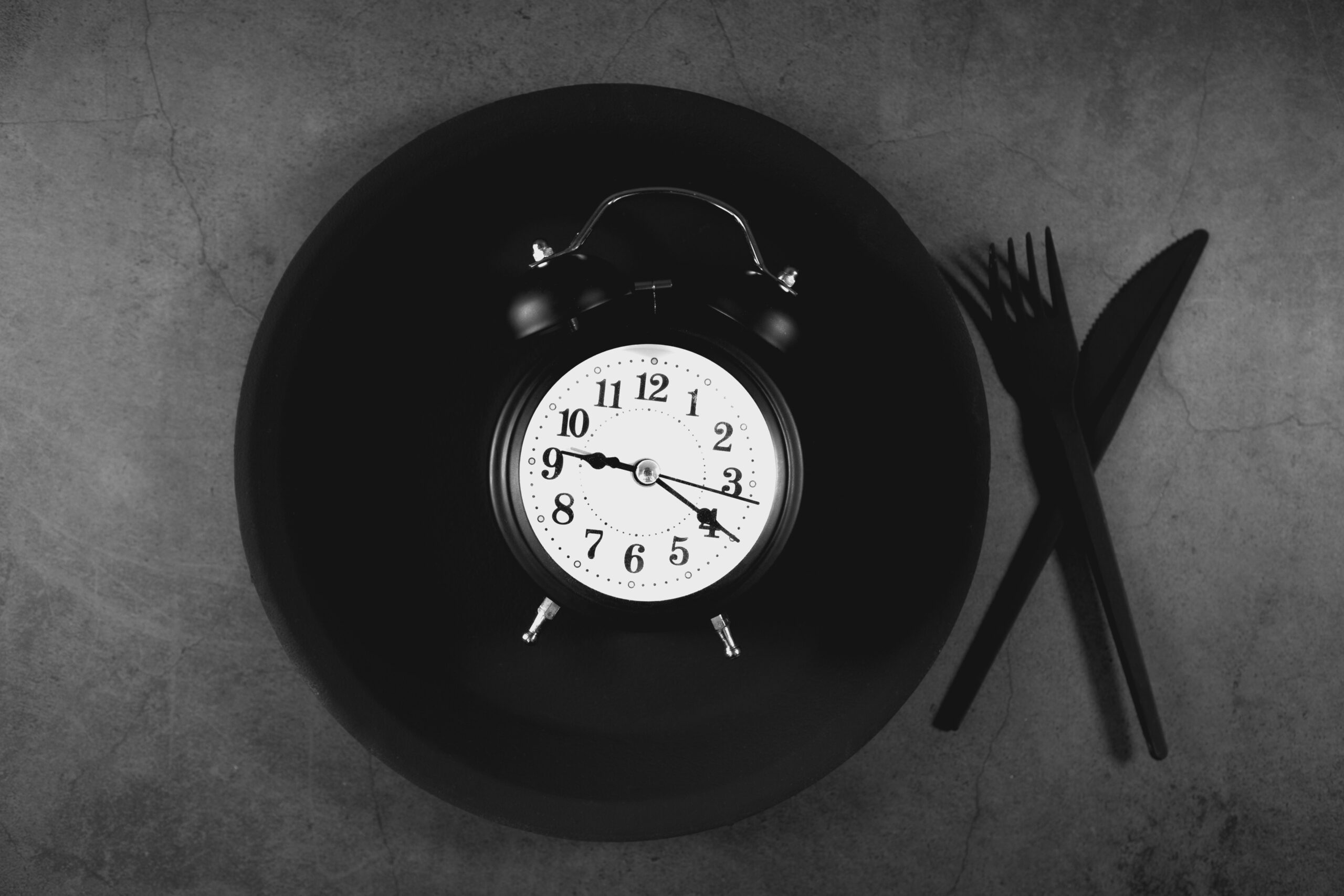 Clock on a plate representing intermittent fasting eating window for men