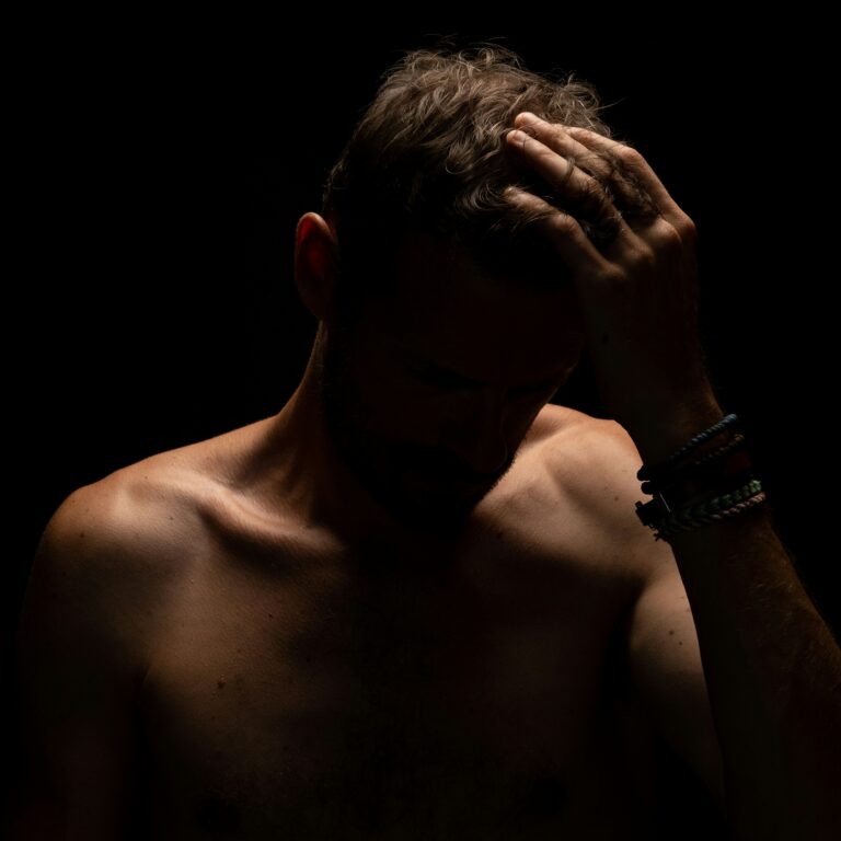 Man with head in hands showing signs of low testosterone and fatigue