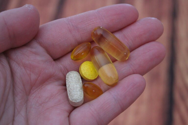 Hand holding a selection of multivitamin tablets and capsules for men over 40