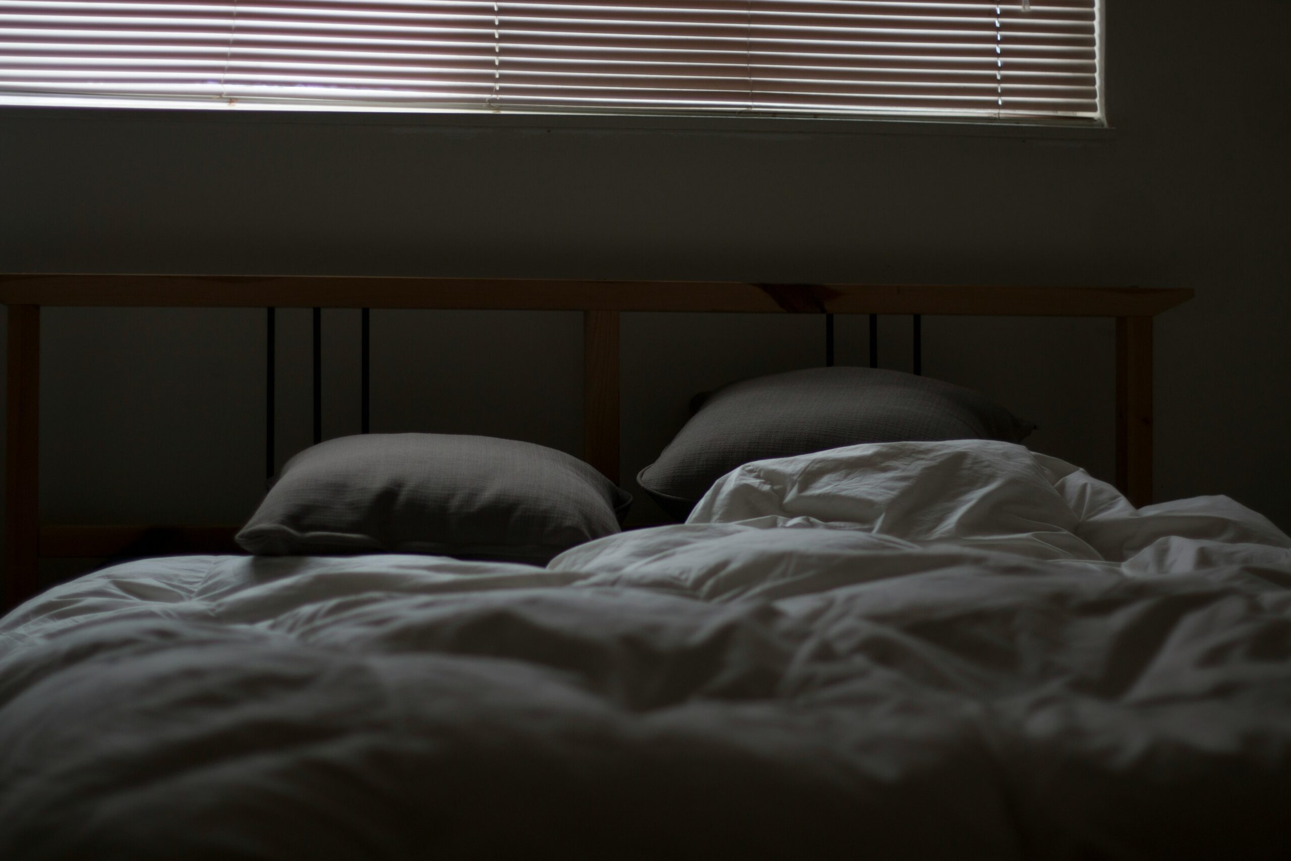 Dark bedroom with unmade bed representing poor sleep and tiredness in dads