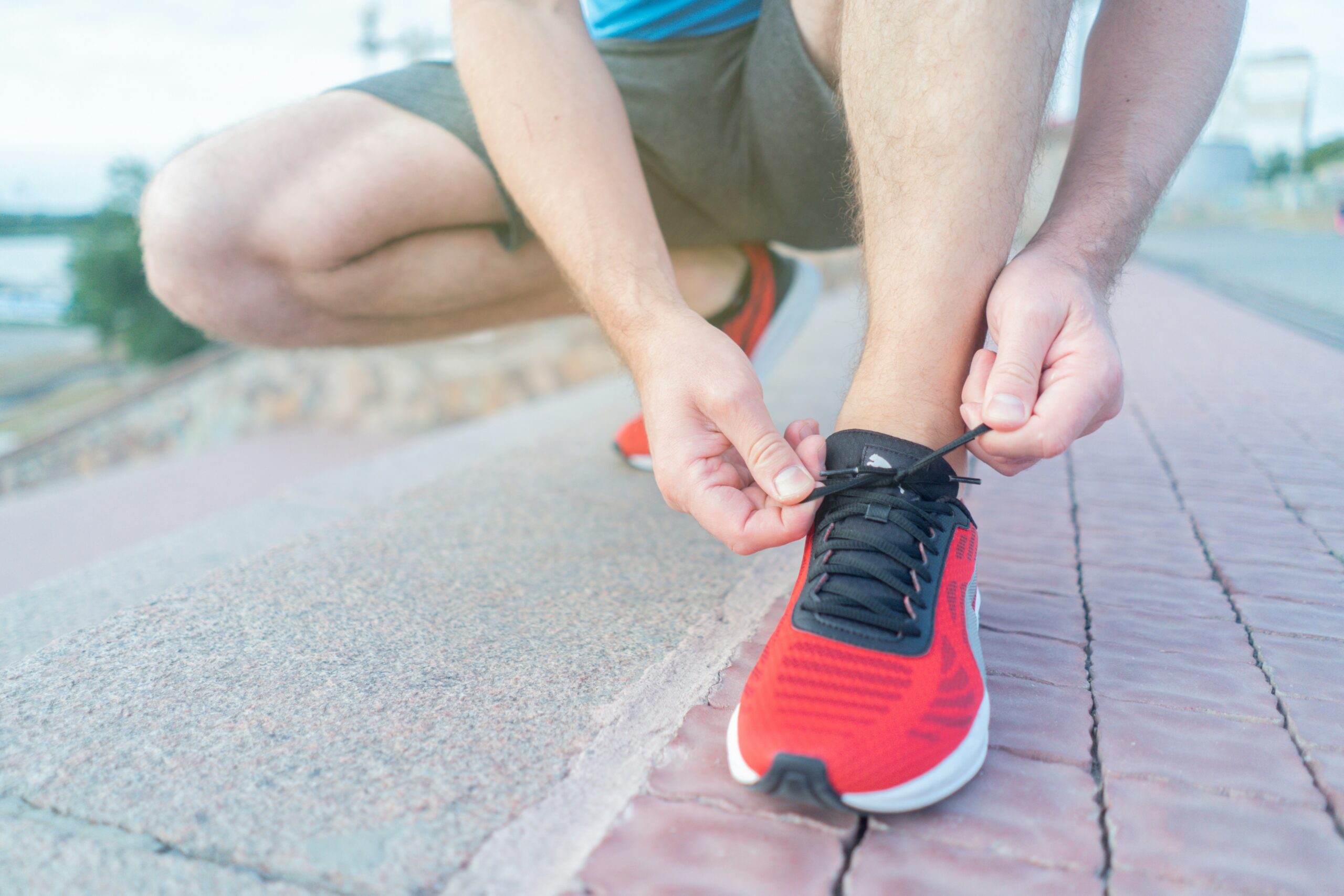 Man tying running shoes outdoors preparing to start running again after a long break