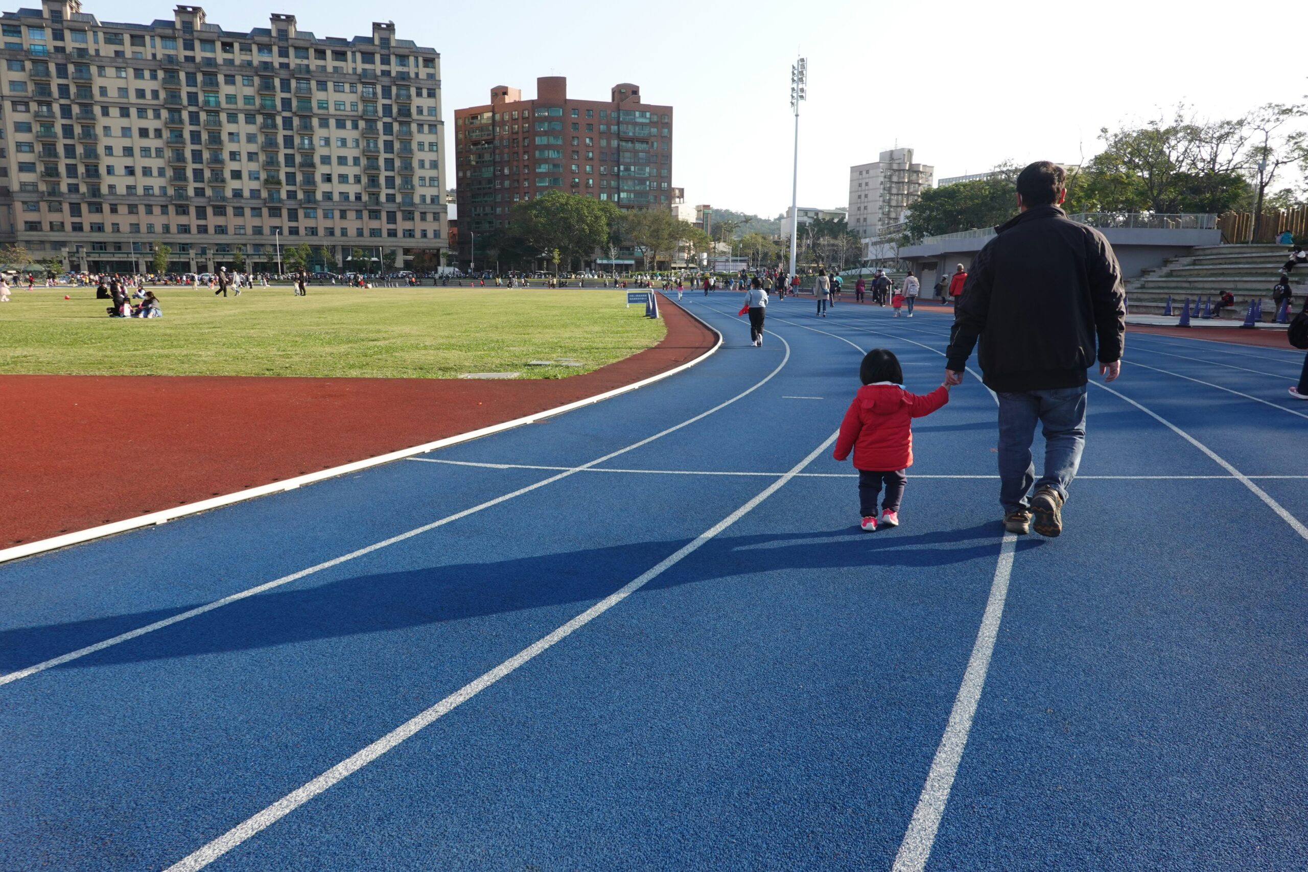 Dad and young child walking together on a running track staying active as a family